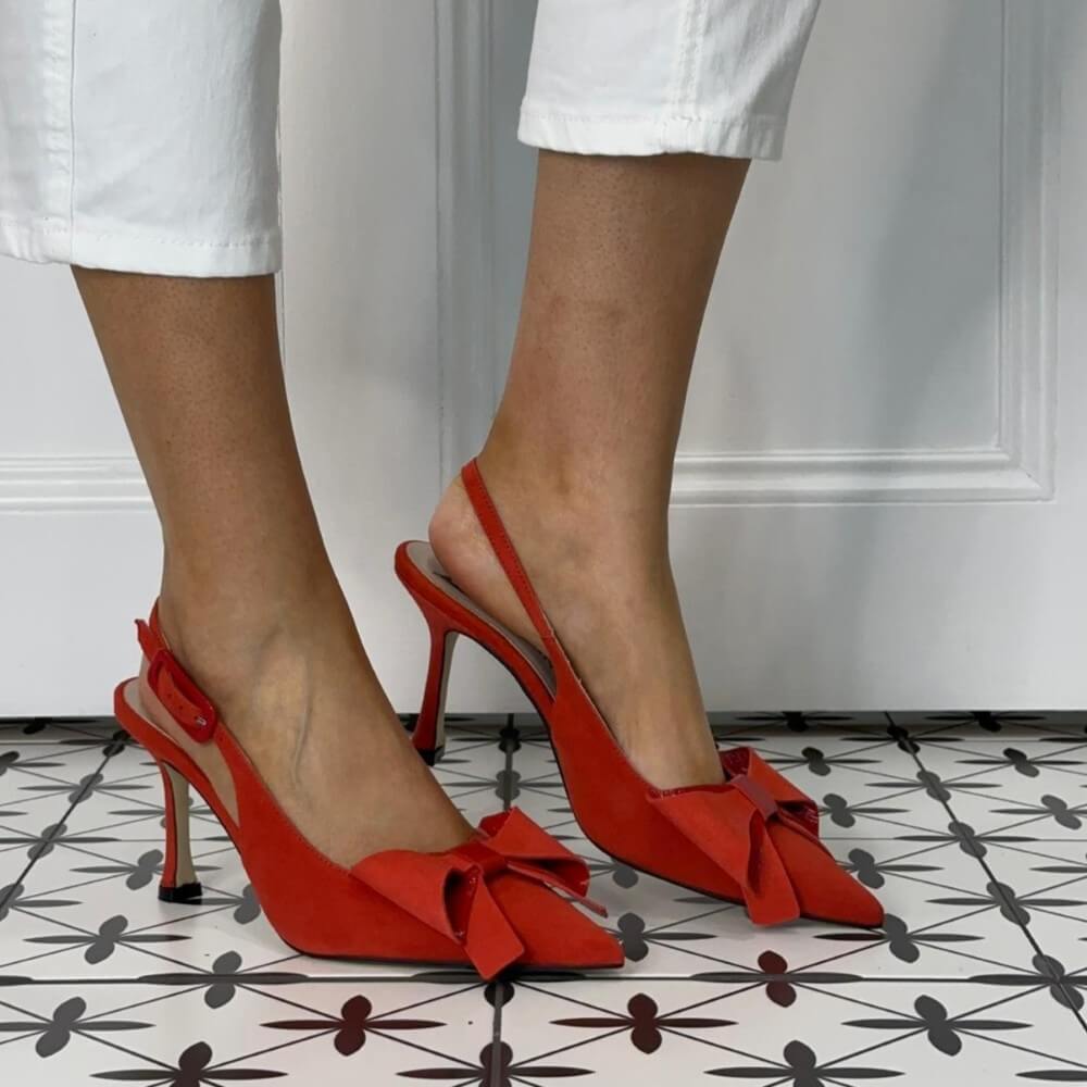 Marian Red high-heeled shoes with a bow detail worn by a person on a patterned floor.