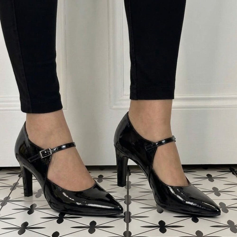 A pair of Marian black patent leather Mary Jane high heels with kitten heels and ankle straps, shown on a model wearing black leggings.