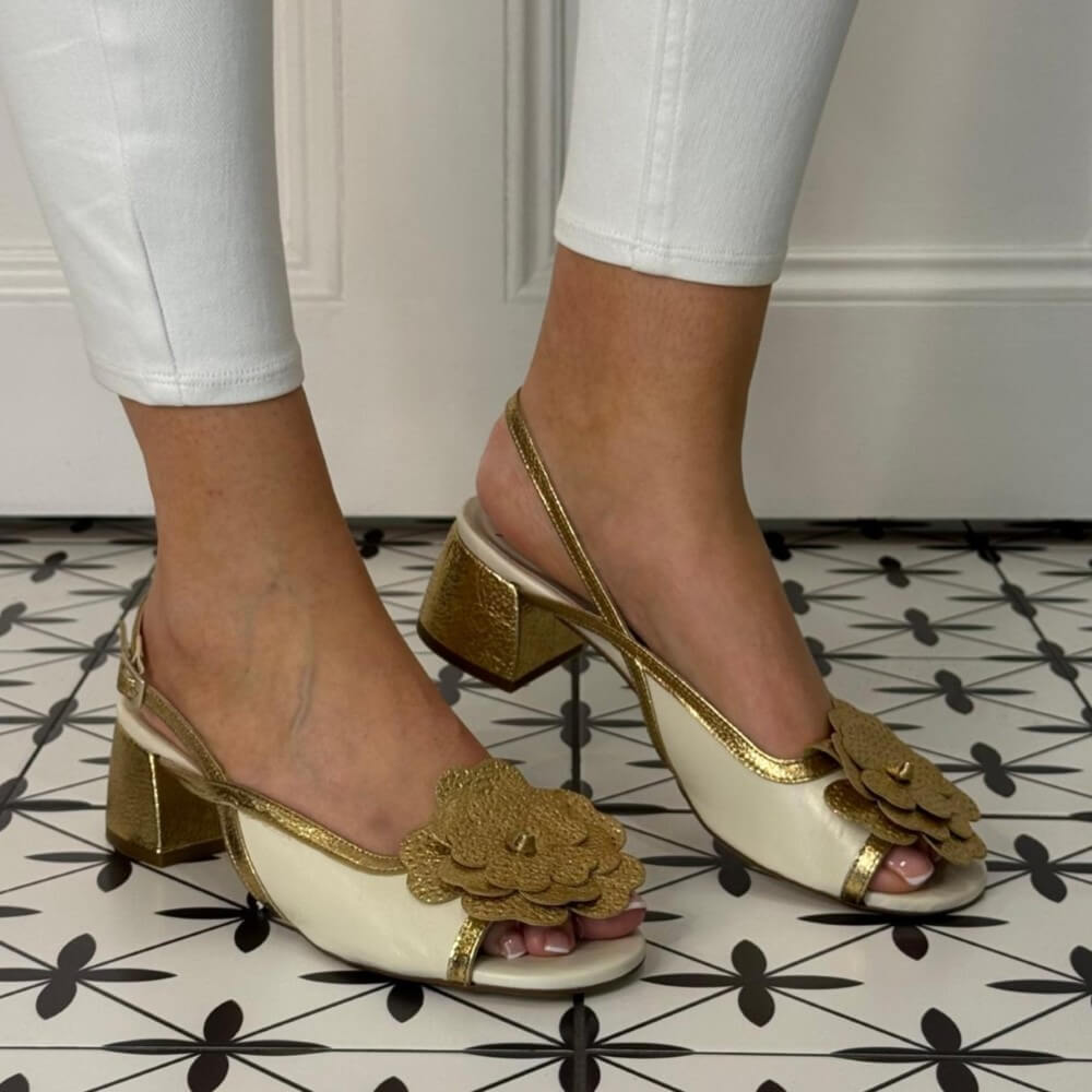 Marian Gold high-heeled shoes with floral details worn on a patterned floor.