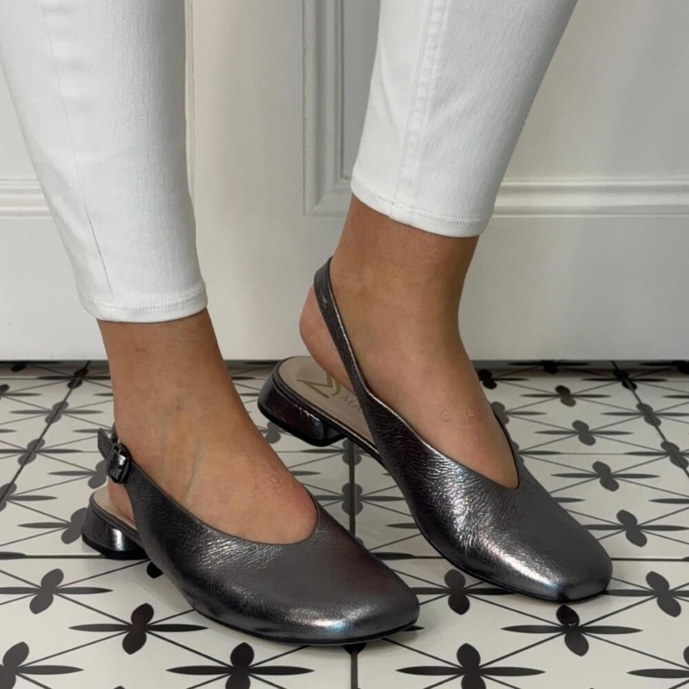 Person wearing Marian metallic silver flats on a patterned floor.