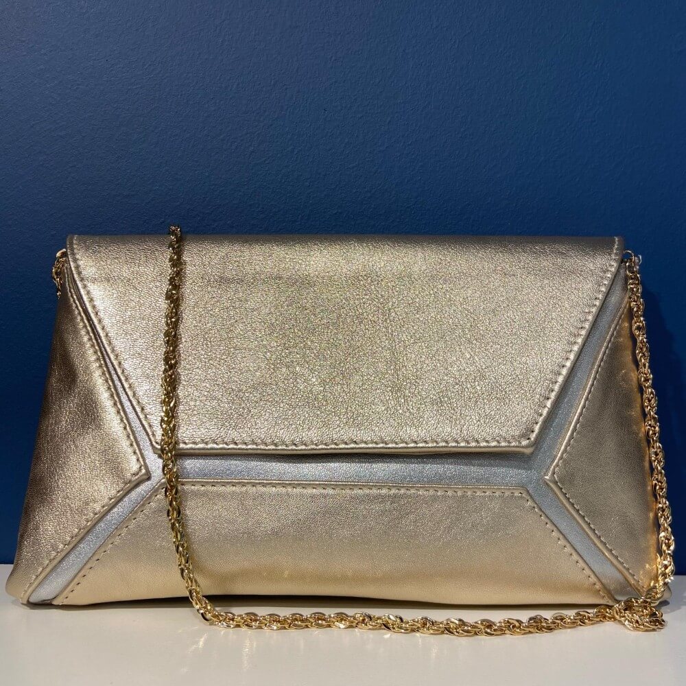 Marian Gold and silver clutch bag with chain strap on a blue background