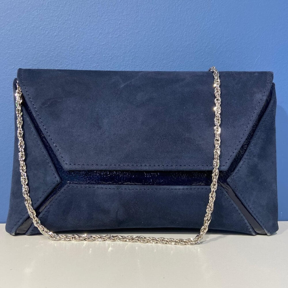 Marian Navy blue clutch bag with a chain strap on a white surface with a blue background