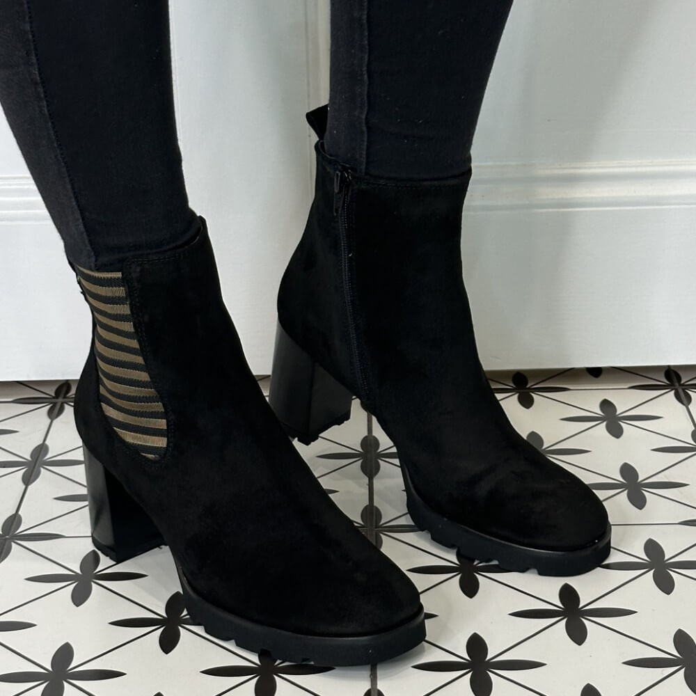 Black Platform ankle boots worn with Gold Detailing, black pants on a patterned floor.