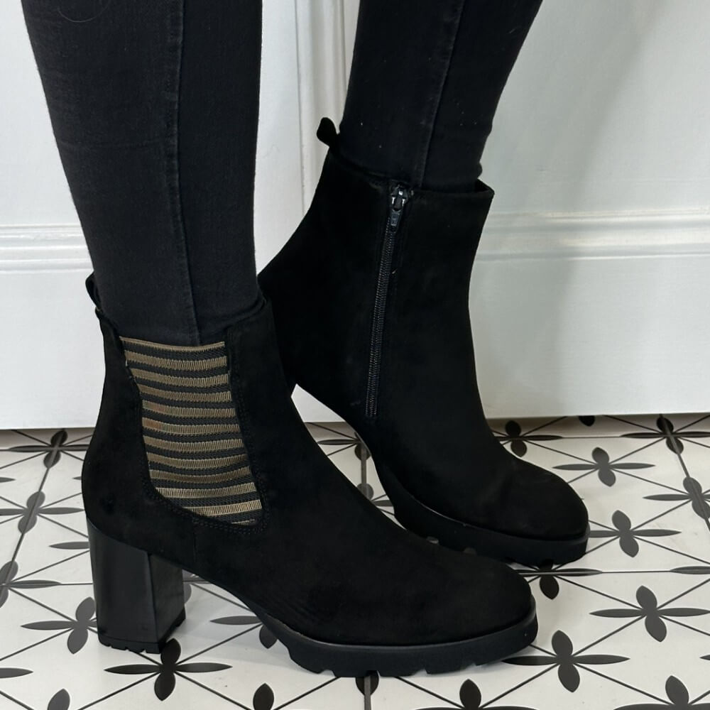 Black Platform ankle boots worn with Gold Detailing, black pants on a patterned floor.