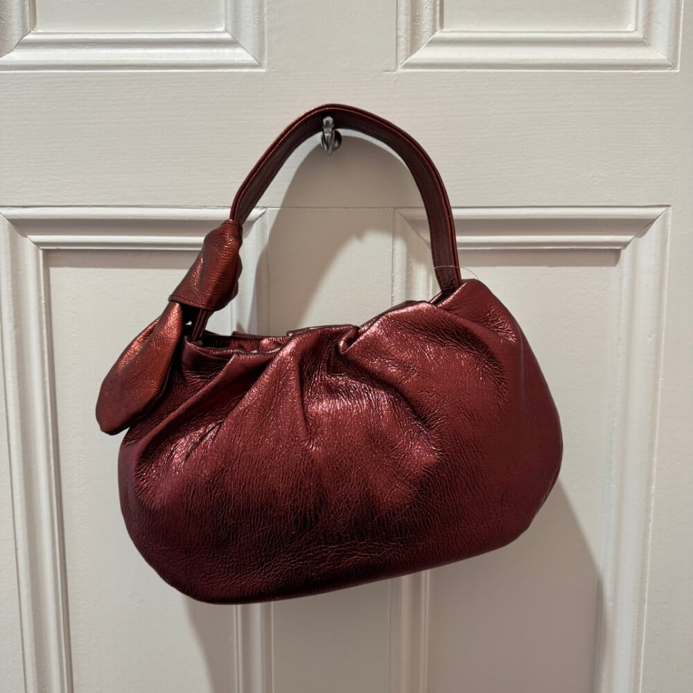 Red handbag hanging on a white paneled door