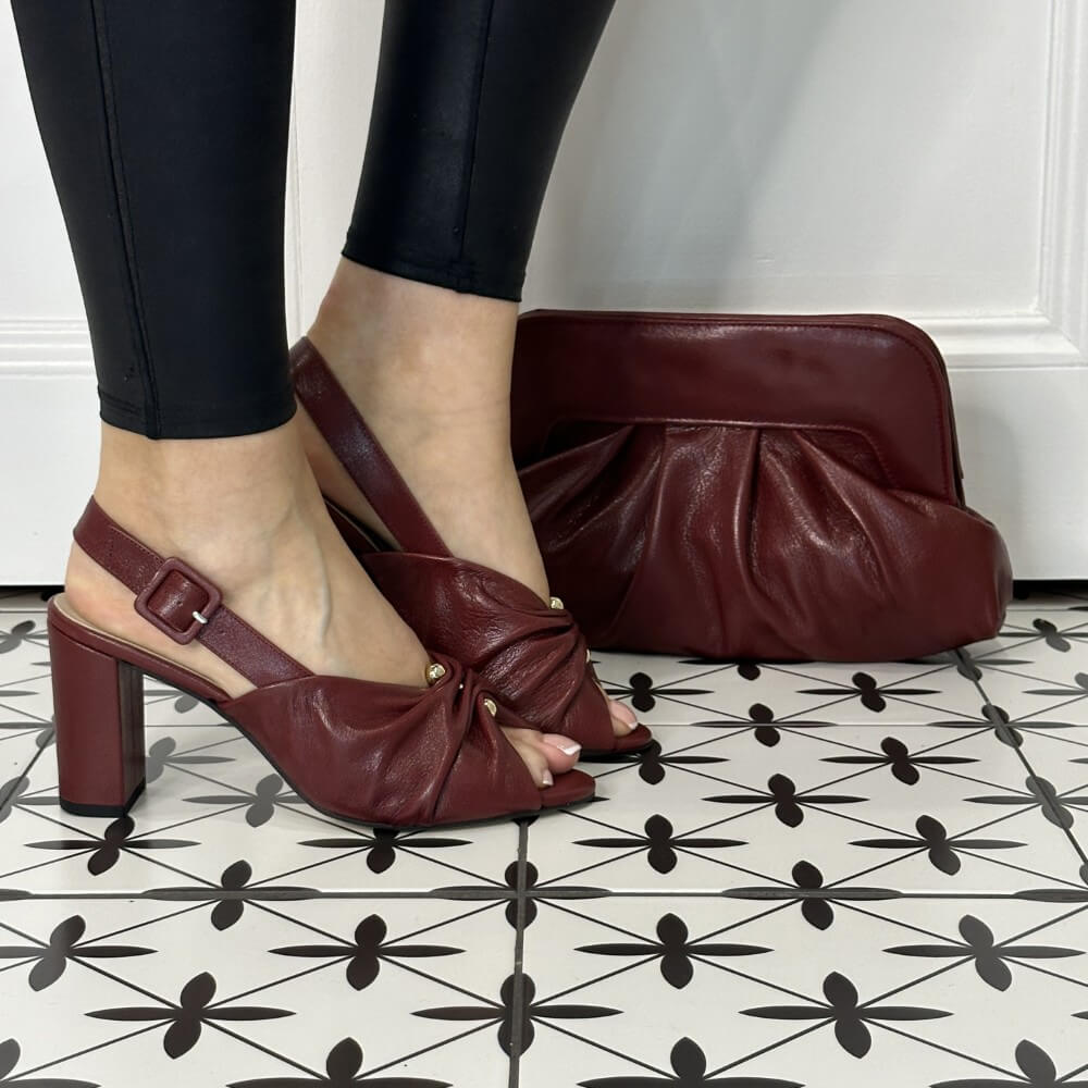 Burgund leather sandals worn with black leggings on a patterned floor.