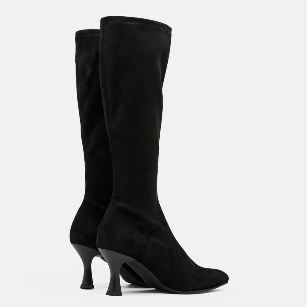 A pair of Miss Elastic black suede knee high boots with pointed toes and slim high heels, shown against a plain light grey background.