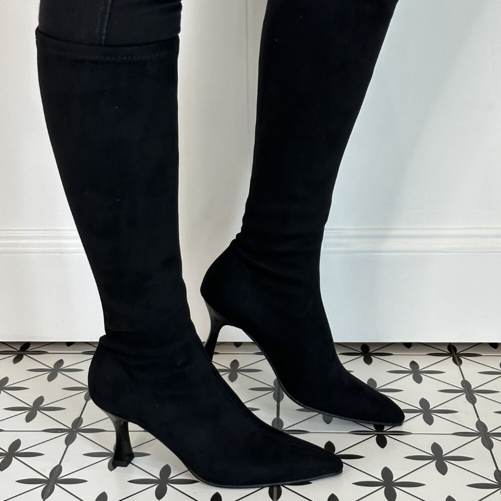 Black knee-high boots worn with black pants on a patterned floor. Miss Elastic 78041 Knee High  Stretch Boot Black