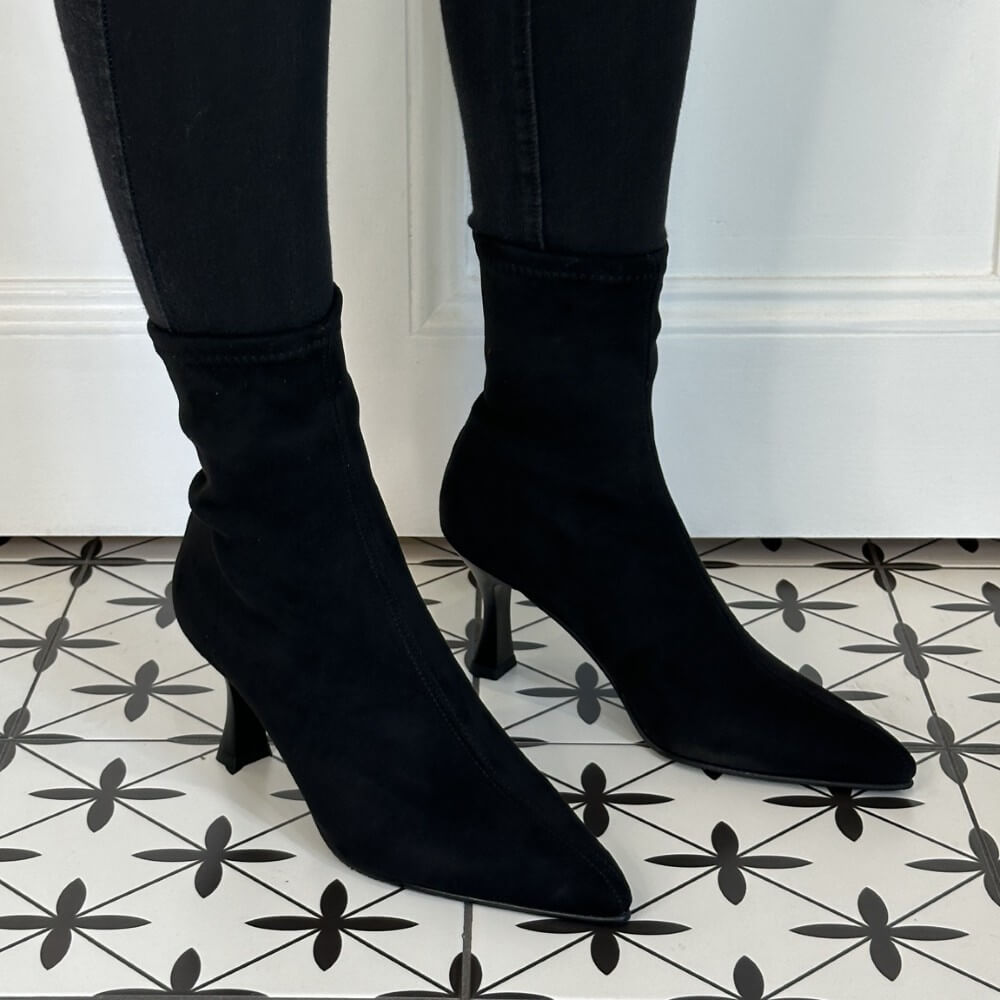 Black sock boots worn with black jeans on a patterned floor. Miss Elastic 78042 Sock Ankle Boot Black