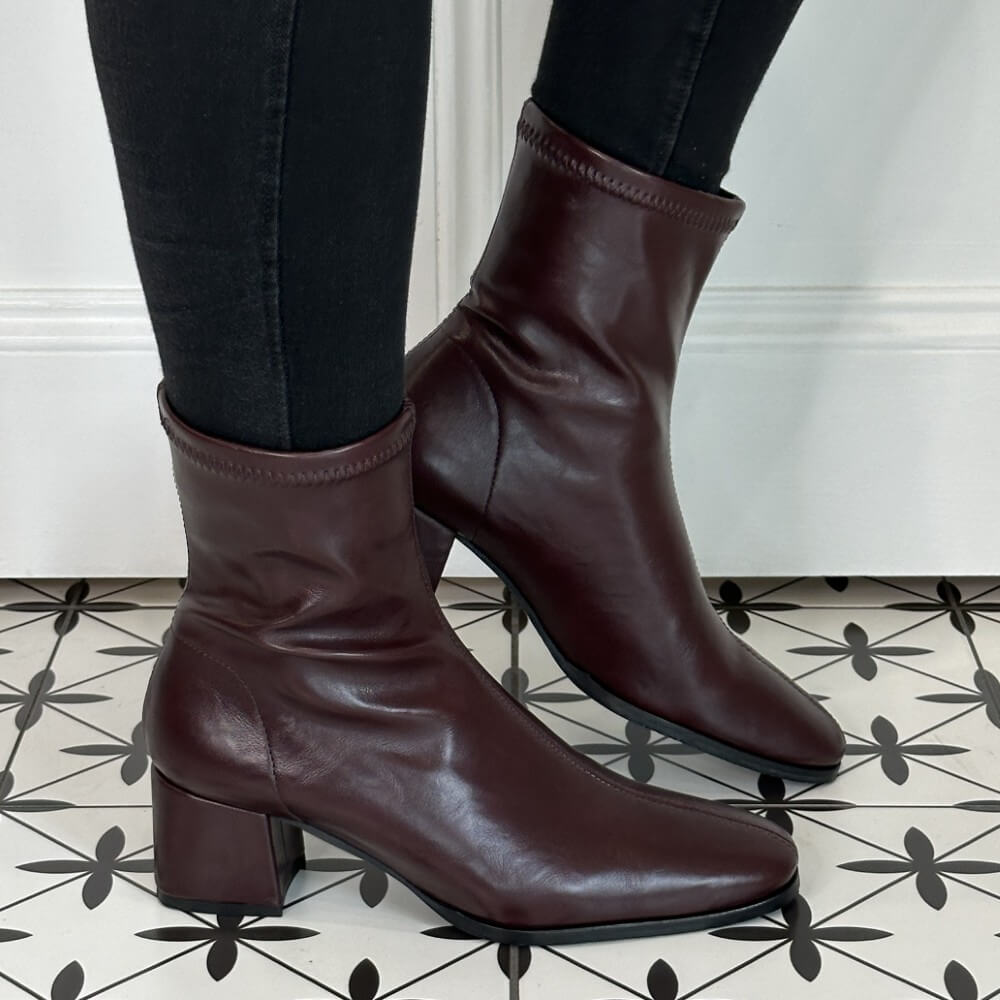 Wine Faux leather ankle boots worn with black pants on a patterned floor. Miss Elastic 78330 Ankle Boot Wine