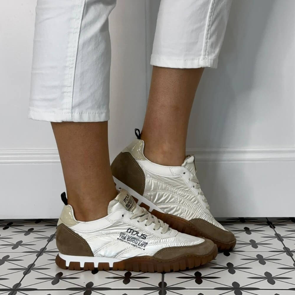 Mjus White sneakers with brown soles worn by a person on a patterned floor.