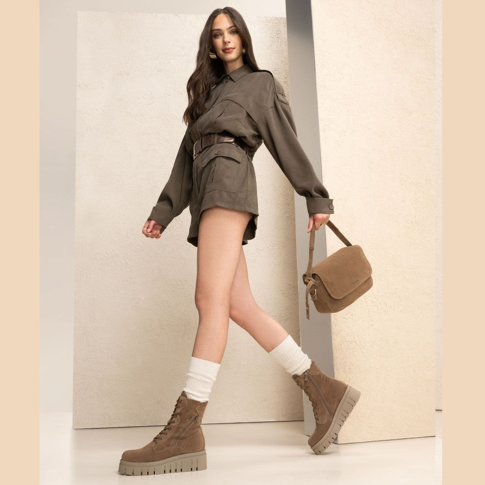 Woman in a stylish outfit with a brown shirt, shorts, and boots, holding a matching bag against a neutral background. Brown suede boot with a platform sole on a white background NeroGiardini Suede combat boots I514911D
