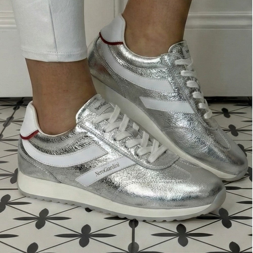 Silver sneakers with white accents worn indoors on a patterned floor. NeroGiardini E615163D