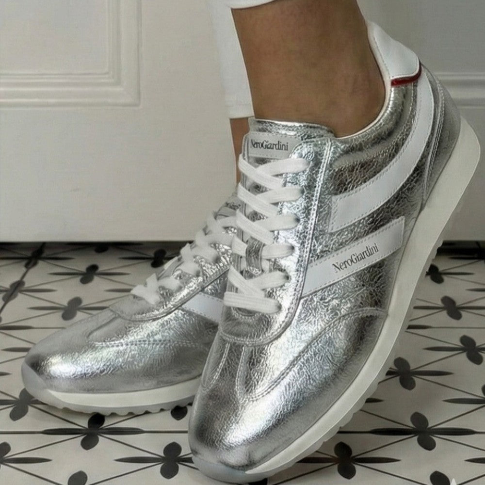 Silver sneakers with white accents worn indoors on a patterned floor. NeroGiardini E615163D