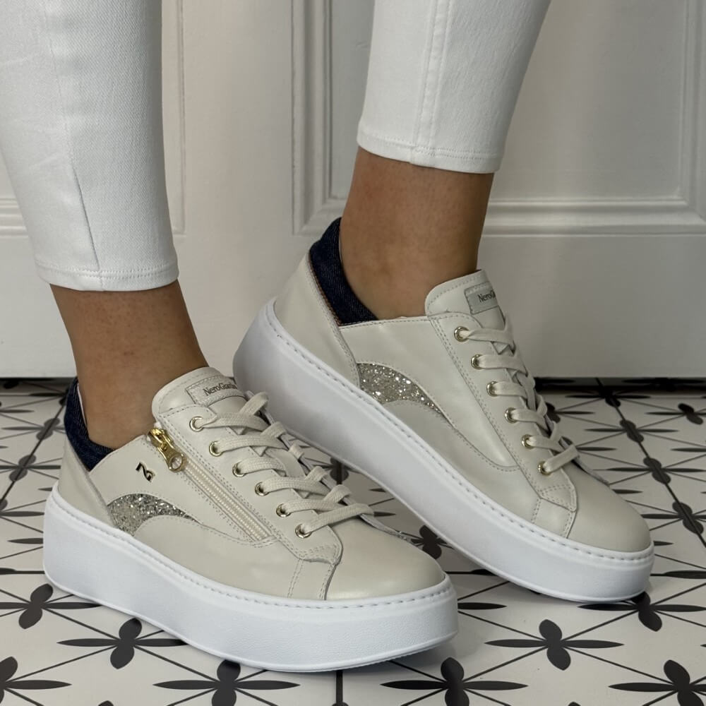 cream sneakers with glittery and denim accents worn by a person on a patterned floor. NeroGiardini E615290D