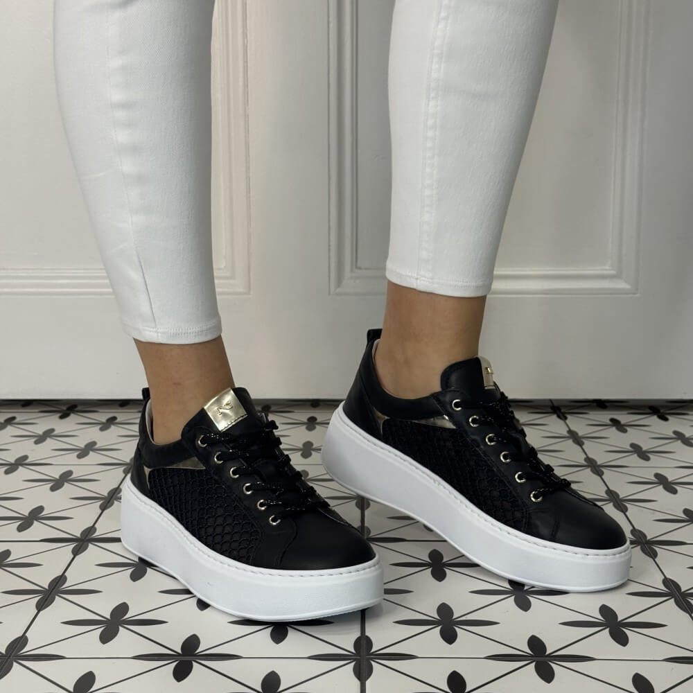 Black Mesh platform sneakers worn with white pants on a patterned floor. NeroGiardini E615292D