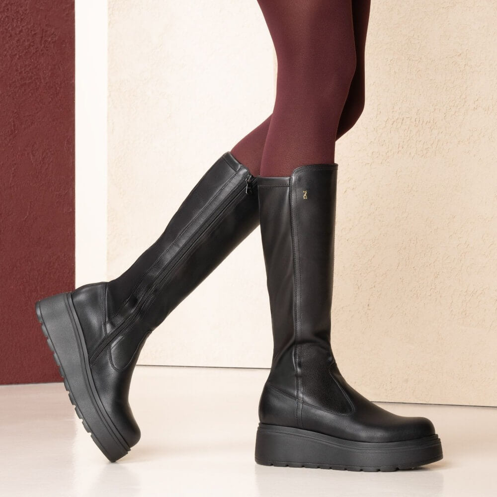 Black knee-high boots worn with burgundy tights on a neutral background   NeroGiardini Knee High Leather Boots I514902D