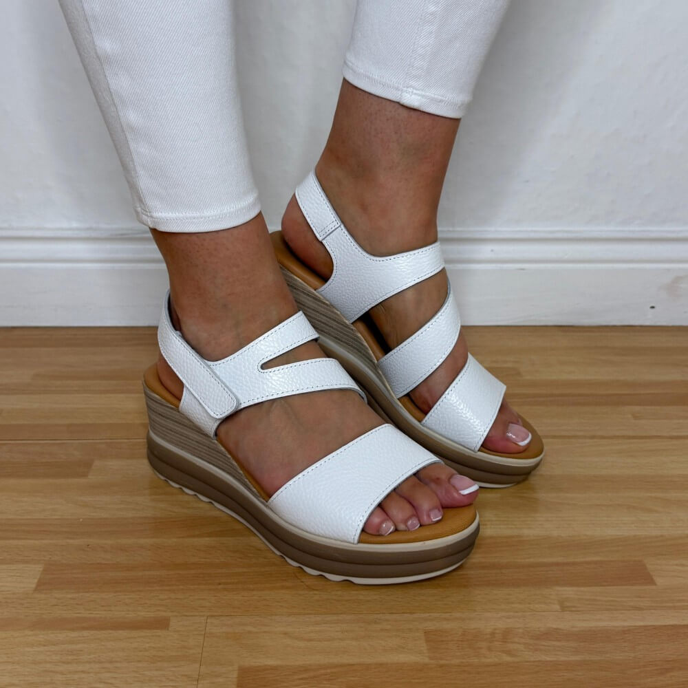 Oh My Sandals 5990 white leather wedge sandals worn with white pants on a wooden floor.