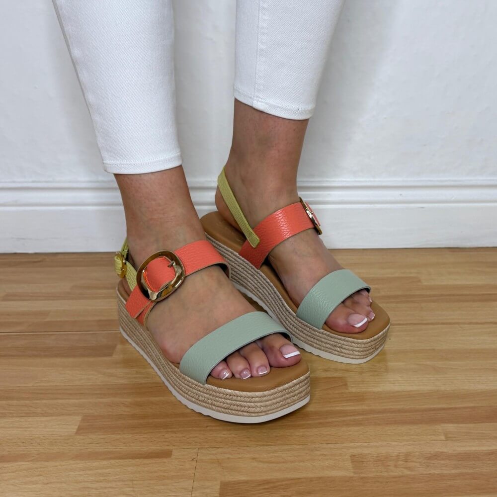 Oh MY Sandals Colourful platform sandals worn with white pants on a wooden floor.