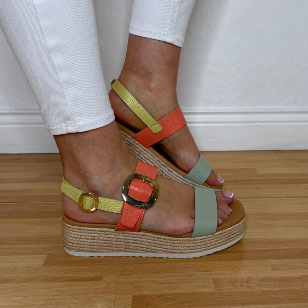 Oh MY Sandals Colourful platform sandals worn with white pants on a wooden floor.