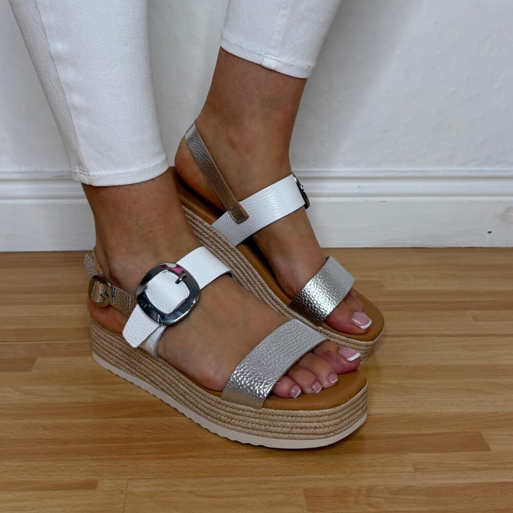 Oh MY Sandals Gold White Wedges on feet with white pants on a wooden floor