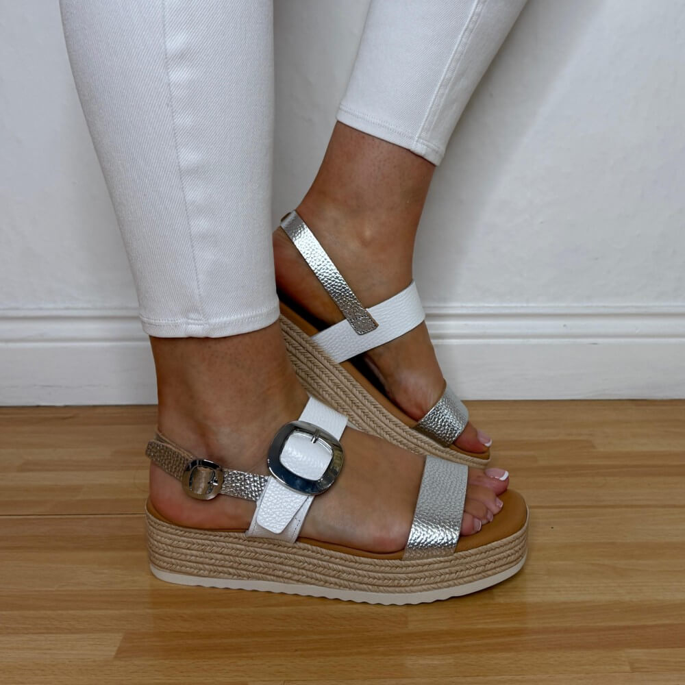 Oh MY Sandals Gold White Wedges on feet with white pants on a wooden floor