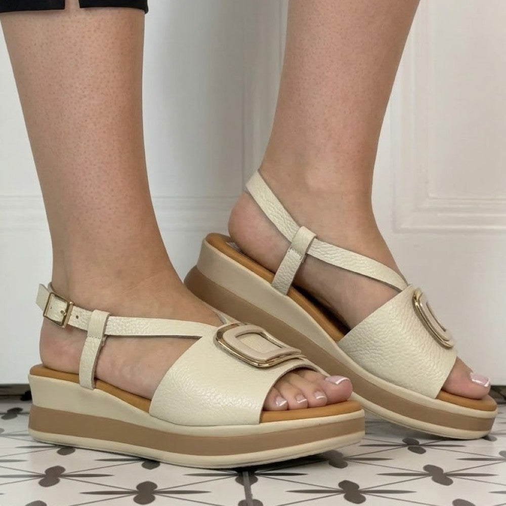 Oh My Sandals Beige sandals with brown soles worn by a person on a tiled floor.
