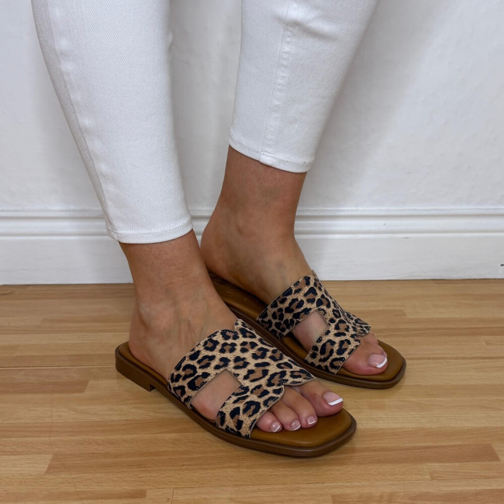 Oh My Sandals 5580 Leopard print sandals worn with white pants on a wooden floor.