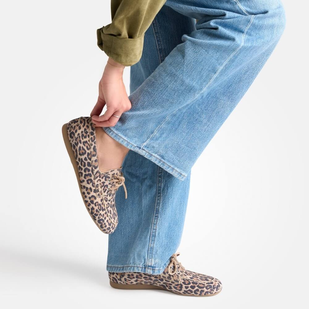 Person wearing Paul Green leopard print shoes with blue jeans on a white background
