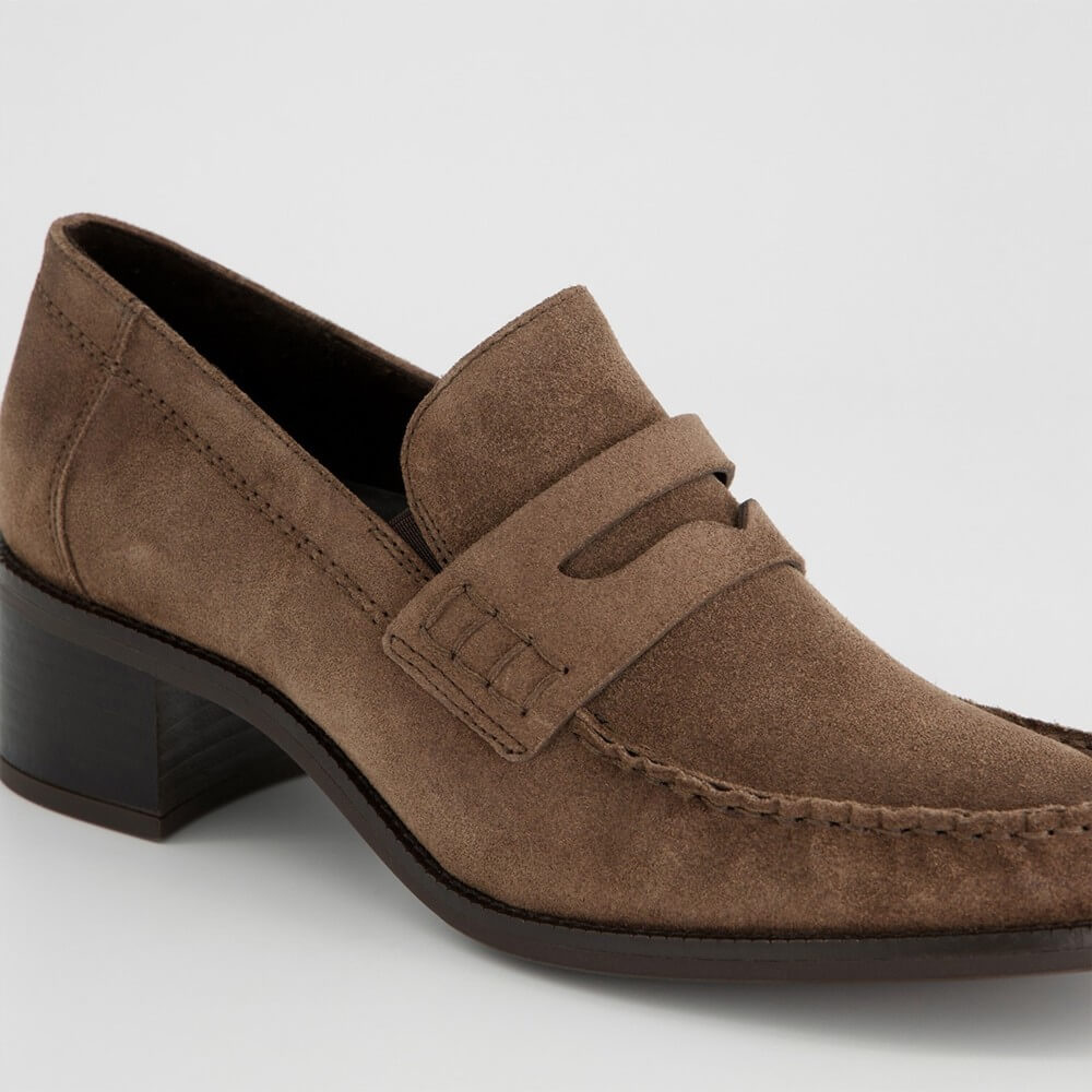A brown suede penny loafer with a low block heel, shown from a three-quarters angle on a light gray background.