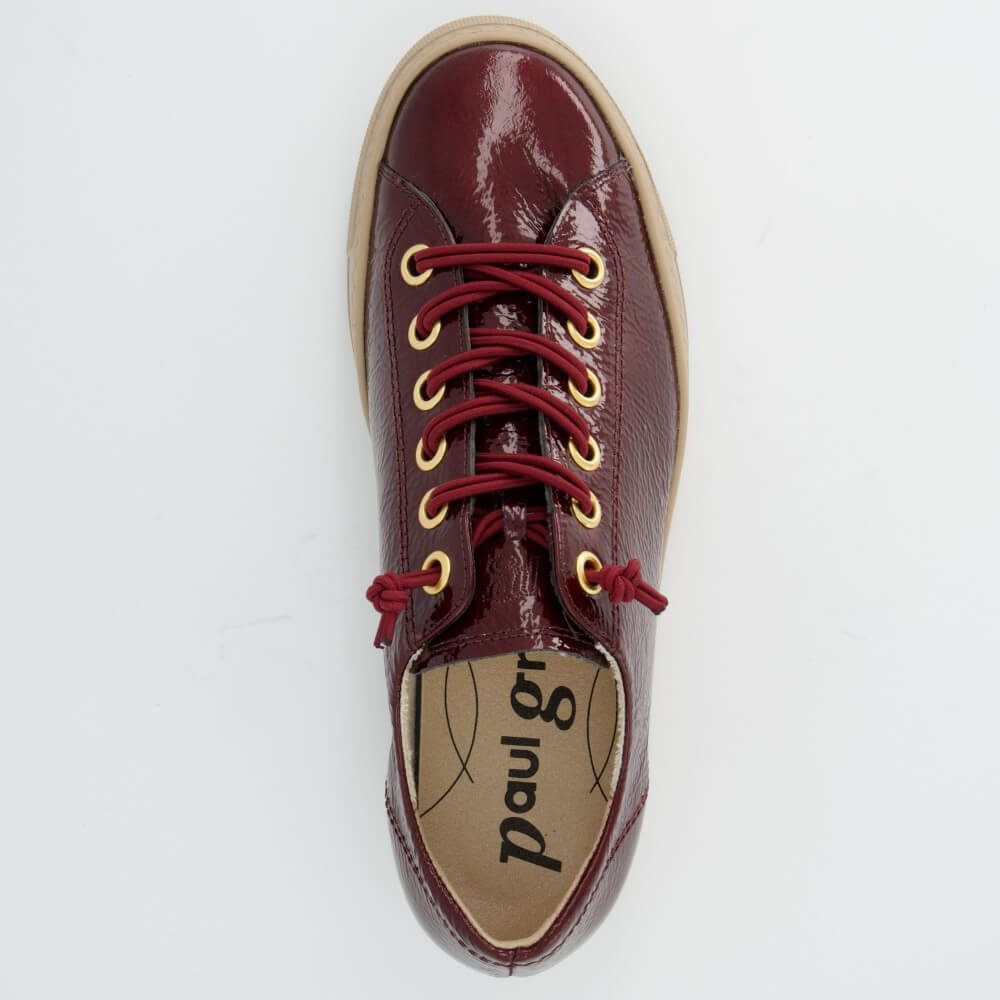 A Paul Green low-top leather sneaker in a deep burgundy red with matching red laces threaded through gold-tone eyelets, featuring a thick beige platform sole, shown against a plain light grey background.