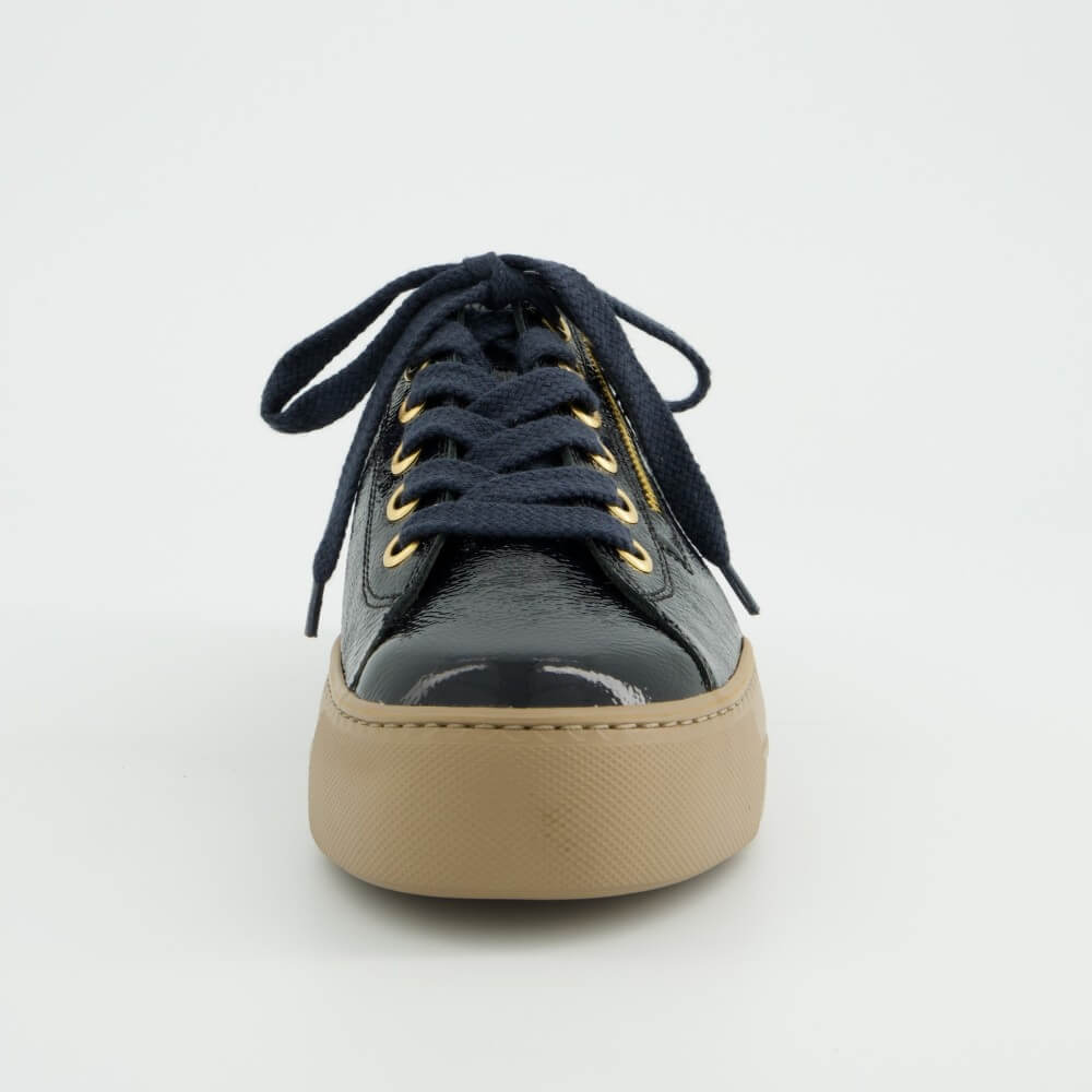 A Paul Green  low-top sneaker in navy blue textured patent leather with a tan sole, navy laces, and gold-tone hardware, shown against a plain light grey background.