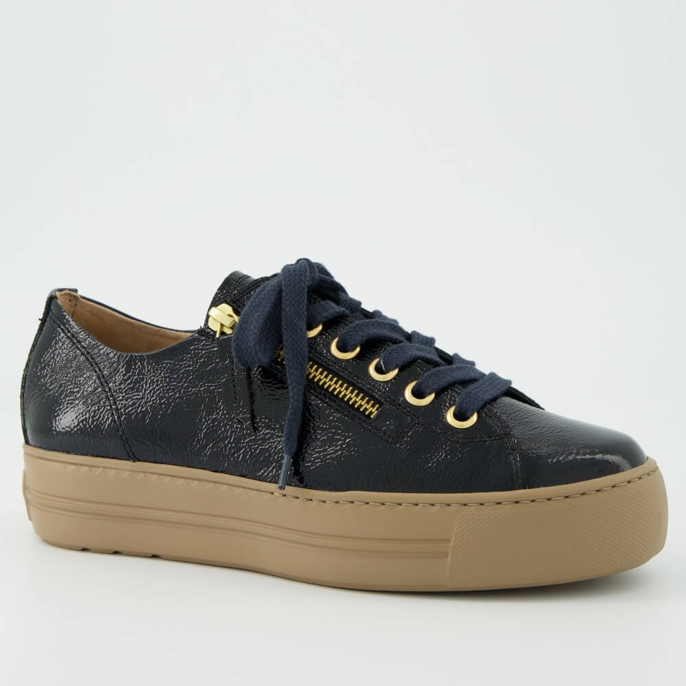 A Paul Green  low-top sneaker in navy blue textured patent leather with a tan sole, navy laces, and gold-tone hardware, shown against a plain light grey background.