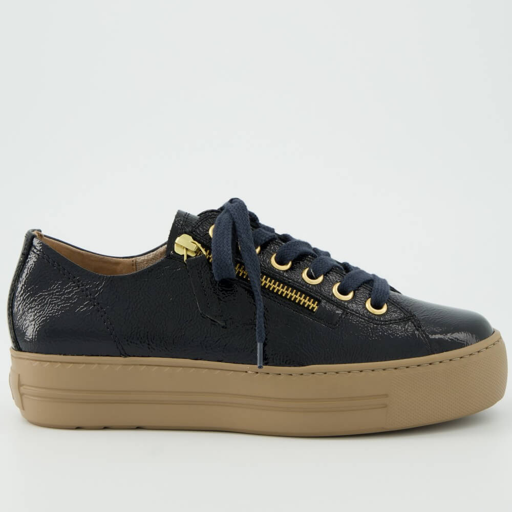 A Paul Green  low-top sneaker in navy blue textured patent leather with a tan sole, navy laces, and gold-tone hardware, shown against a plain light grey background.