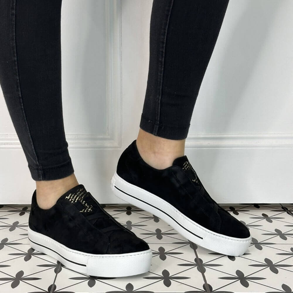 Person wearing elastic Black Leather Trainers with a white sole