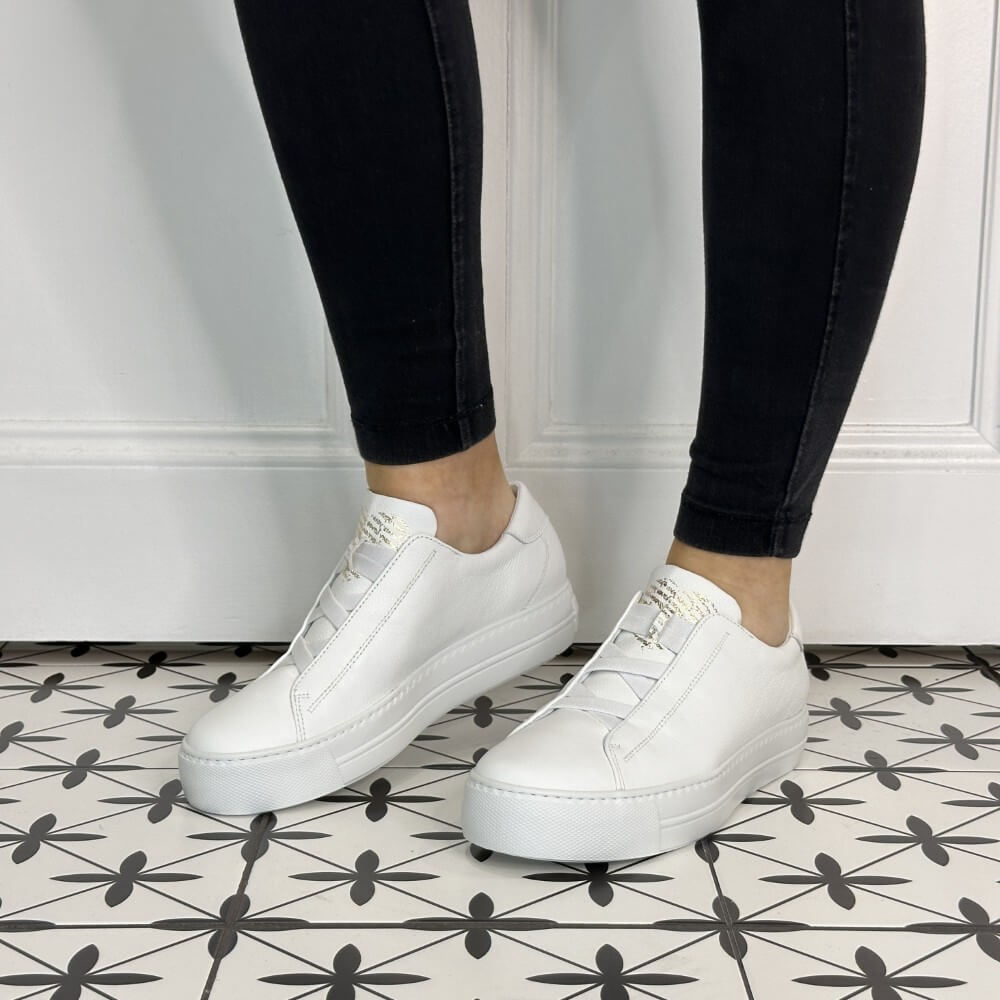 Person wearing white leather slip-on trainers