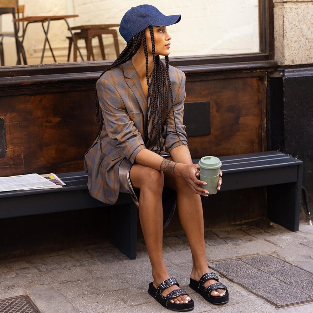 Woman sitting on a bench holding a coffee cup 