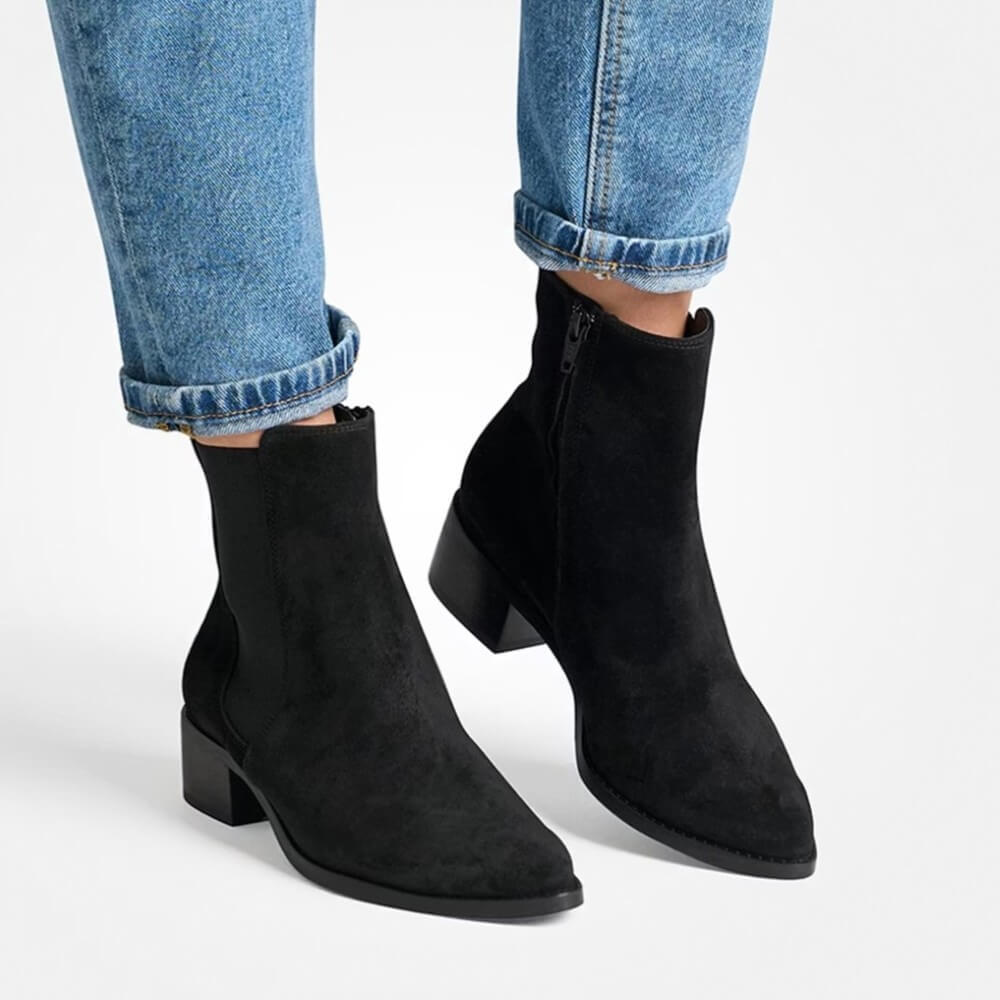 Black ankle boots worn with blue jeans on a light gray background  Chelsea ankle boots 8271 by Paul Green 