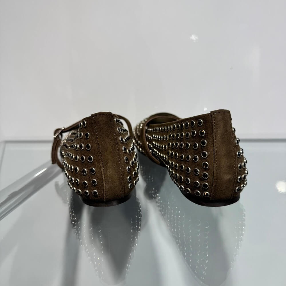 A pair of Pedro Anton Khaki Green flat shoes decorated with silver-tone metal studs and a matching Khaki strap with a silver buckle, shown against a plain white background.