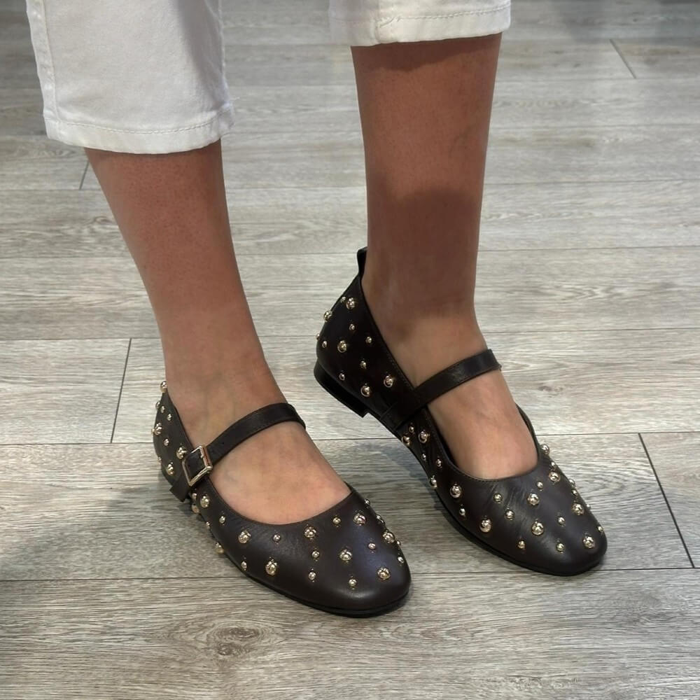Pedro Anton Brown studded flats worn on a wooden floor