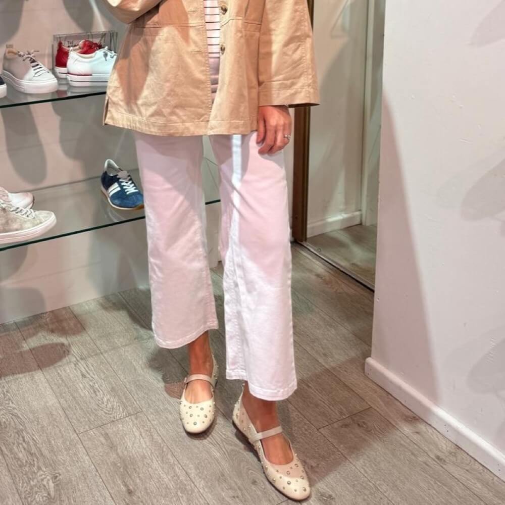 Pedro Anton Beige studded flats worn with light-coloured pants on a wooden floor.