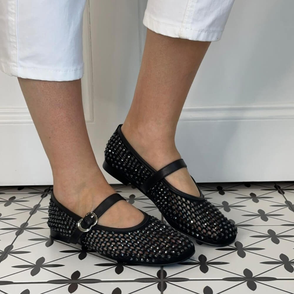 Pedro Anton Black crystal woven shoes with a strap worn by a person on a patterned floor.
