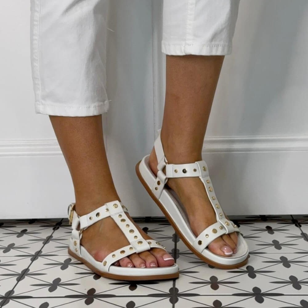 Pedro Anton White sandals with gold accents worn by a person on a patterned floor.