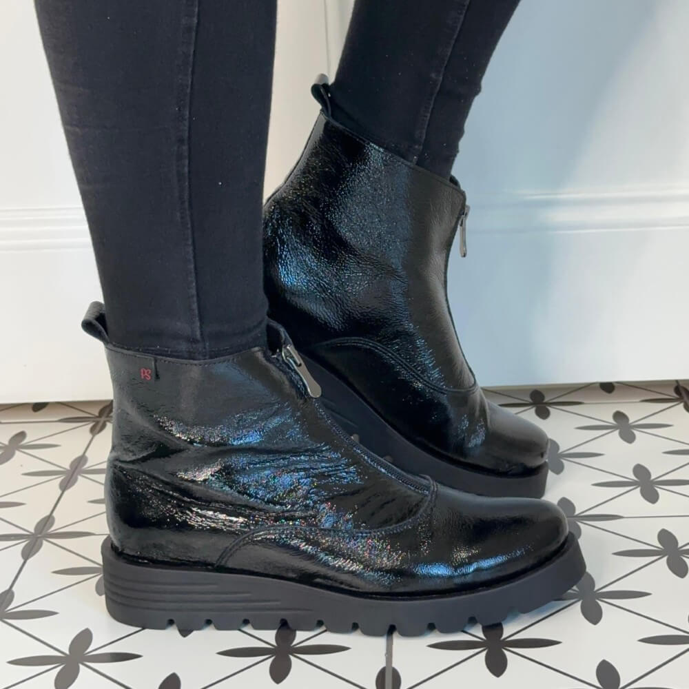 Black patent boots worn with black pants on a patterned floor. Pepe Saenz Wedge Patent Leather Ankle Boots 21544 Black