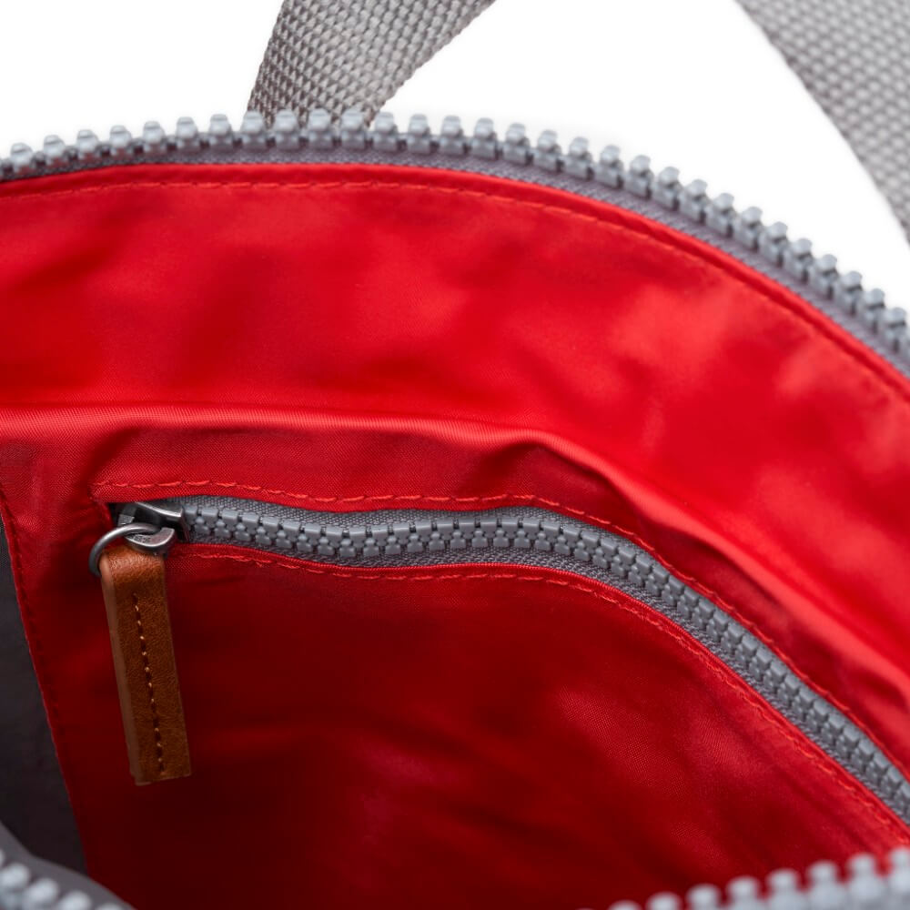 Close-up of a red bag with a zipper and brown pull tab.