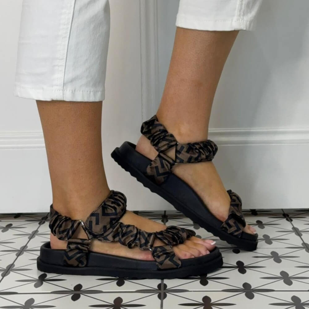 Repo Black sandals with leopard print straps worn by a person on a tiled floor.