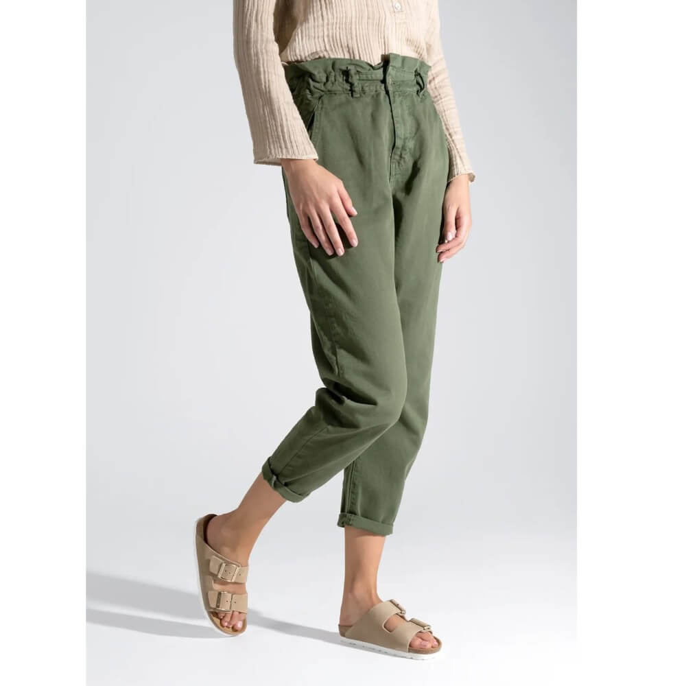 Person wearing green pants and Rohde beige sandals on a white background