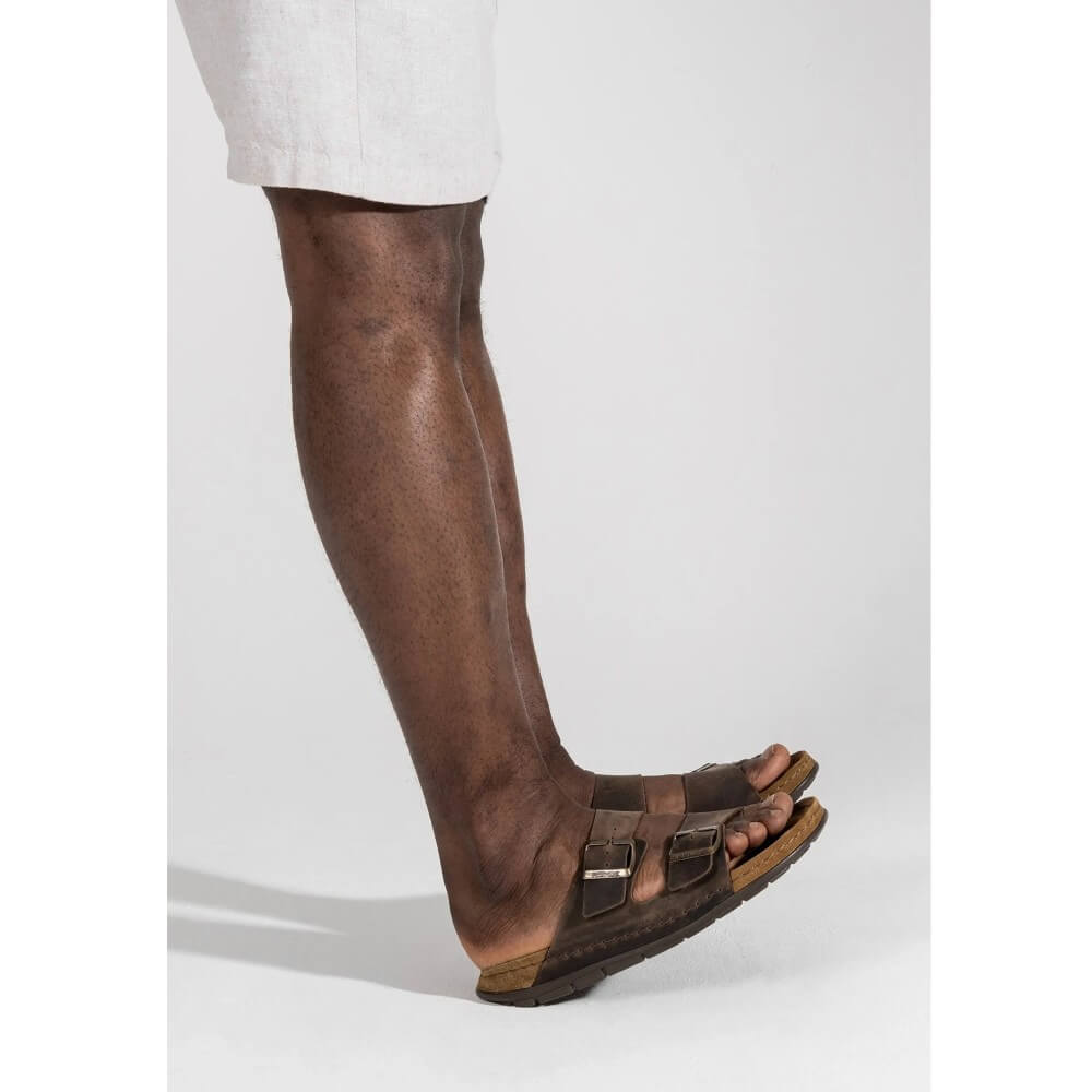 Person wearing Rohde Brown sandal with double buckle design on a white background