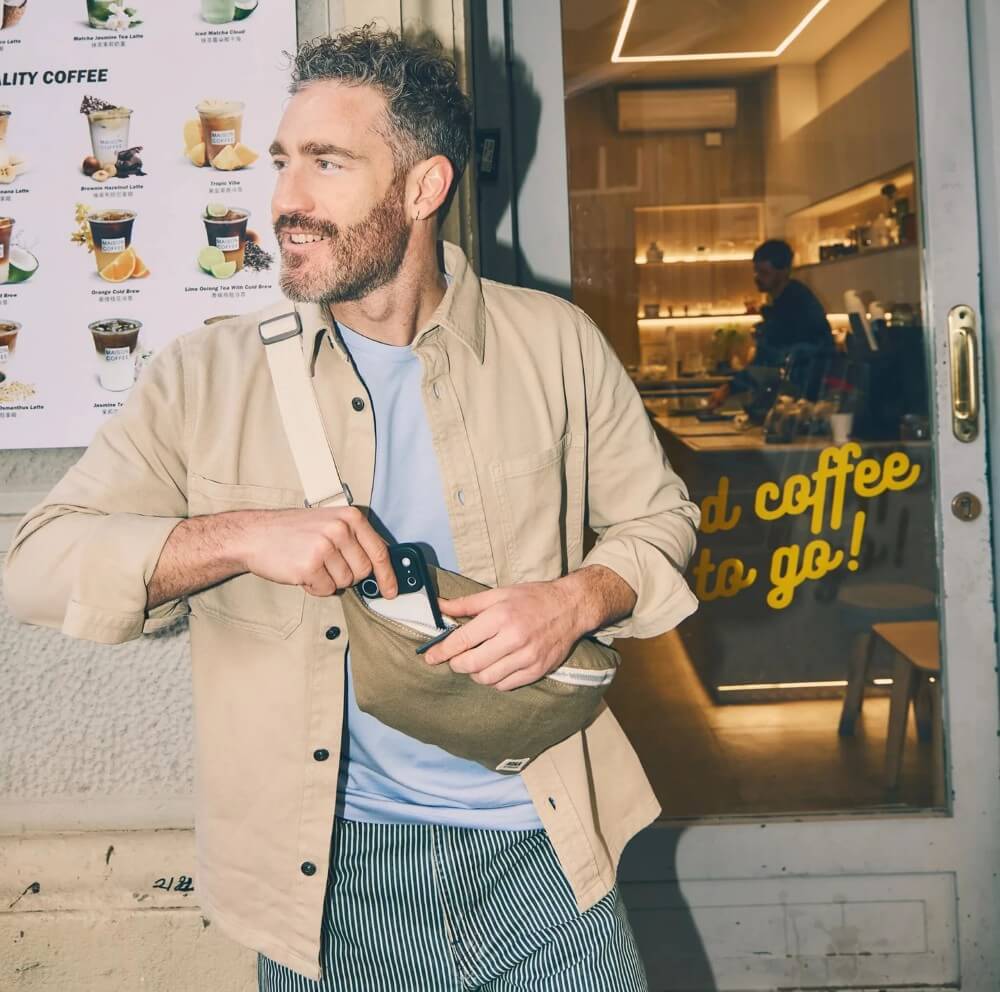 Man wearing a Roka bag outside a coffee shop
