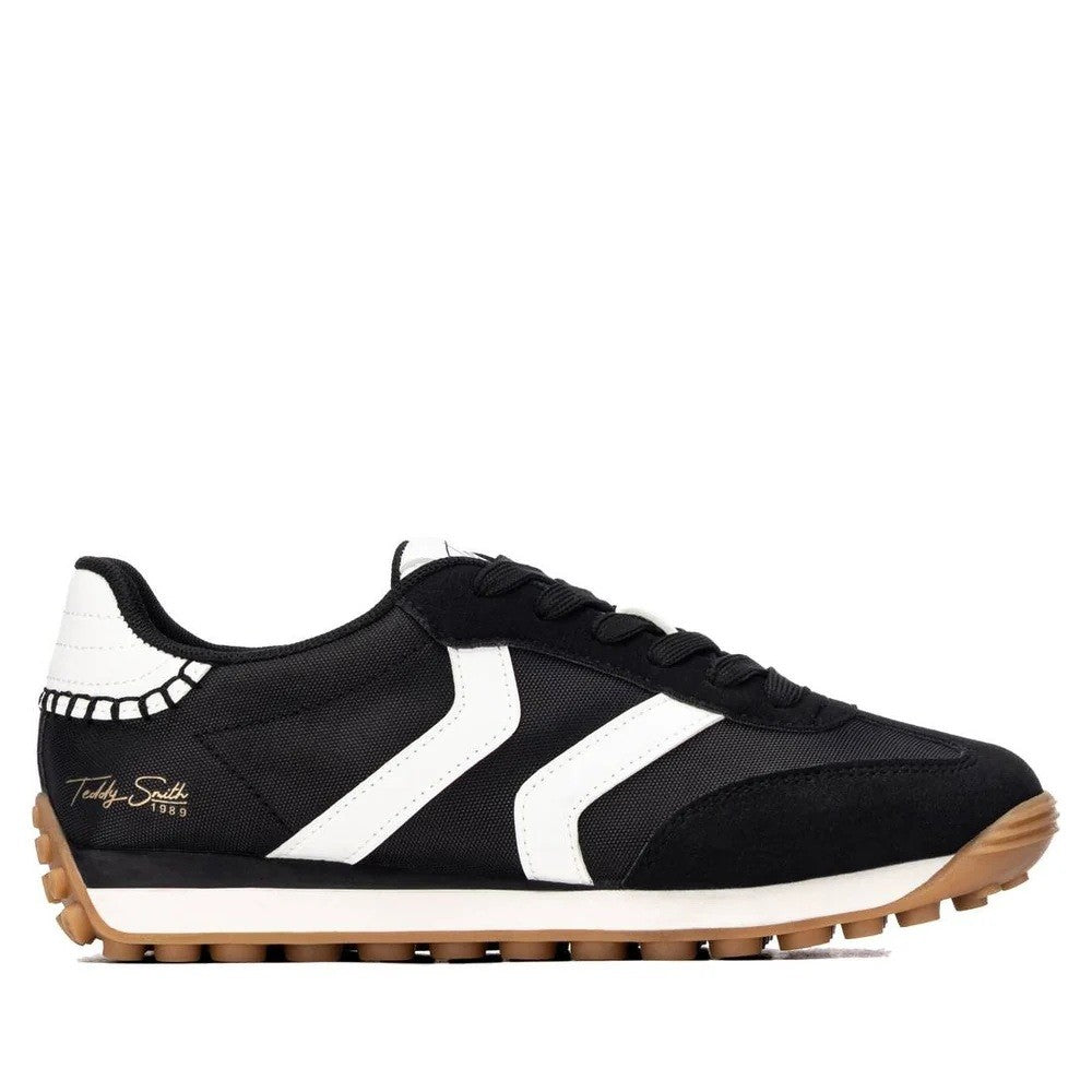A black and white low-top sneaker with a gum rubber sole, featuring a white chevron stripe on the side, a white heel tab and gold 'Teddy Smith' on the heel